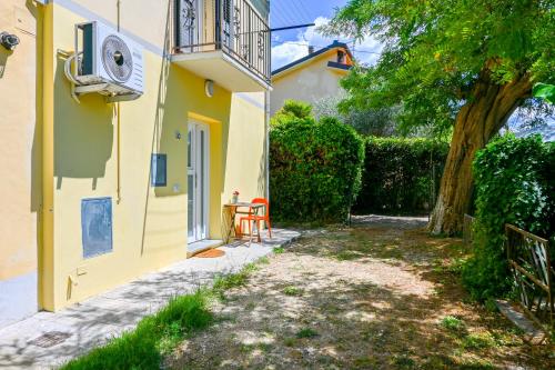 a yellow house with a tree and a chair at InnPisaRentals - Cozy Flat by the Airport in Pisa