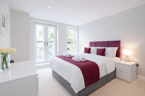 a white bedroom with a large bed and windows at Roomspace Serviced Apartments - Trinity House in Reigate