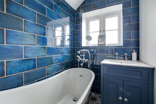 a blue tiled bathroom with a tub and a sink at 3 Bed in Kelling oc-w27424 in Kelling