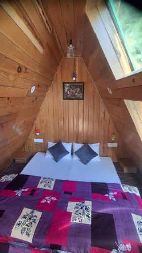 a bedroom with a bed in a wooden attic at Pinehill cottage in Jibhi