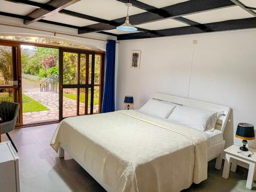 a bedroom with a white bed and a large window at ARAUCARIA RESIDENCE in Gisenyi