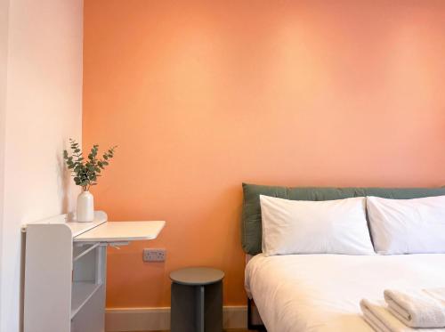 a bedroom with an orange wall and a bed at Zozy Clitterhouse in London
