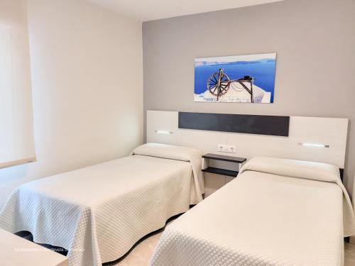 a room with two beds and a flat screen tv at Apartamento Mardevela in Sanxenxo