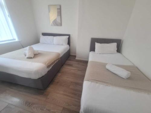two beds in a small room with wooden floors at Homely 2 Bedroom Dudley in Seaton Burn