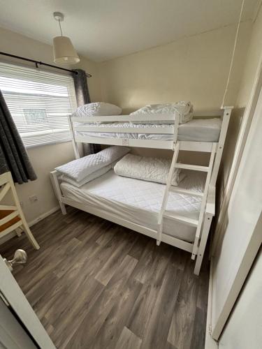 two bunk beds in a room with a wooden floor at 192, Two bed newly refurbished chalet on Sund0wner Holiday Park - Sleeps 5, pet friendly - Includes electricity, bed linen and towels - Entertainment options close by in Hemsby