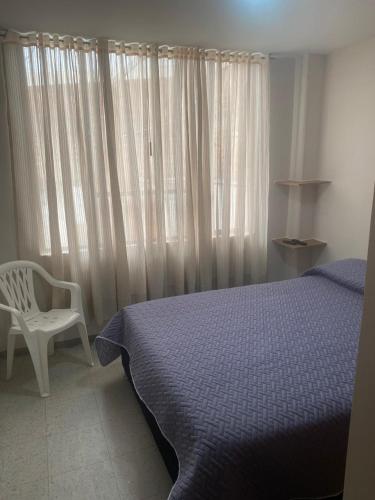 a bedroom with a bed and a chair next to a window at Siéntete en casa 2 in Pasto