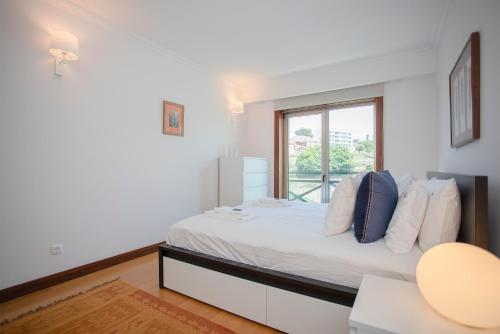 a white bedroom with a bed and a window at Liiiving in Porto - Douro Riverside Apartment in Porto