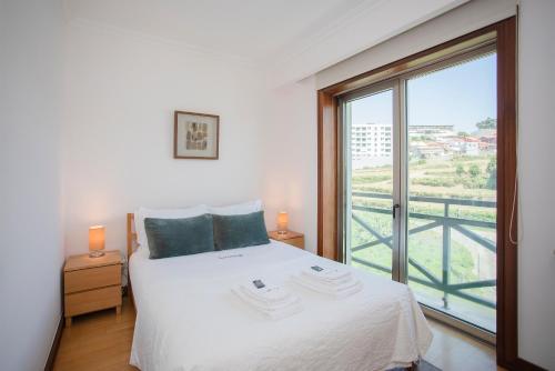a bedroom with a white bed and a large window at Liiiving in Porto - Douro Riverside Apartment in Porto
