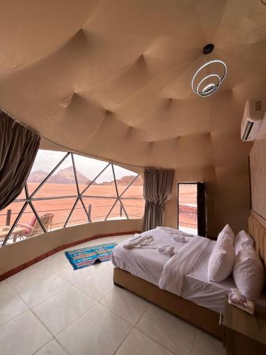 a bedroom with a large bed and a large window at Wadi rum camp teem in Wadi Rum