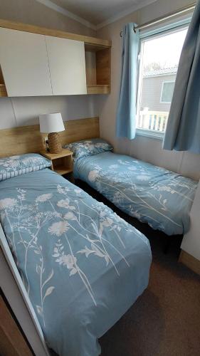a bedroom with two beds and a window at Driftwood at Freshwater Beach Holiday Park in Burton Bradstock