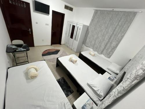 a room with two beds and a window at ALEX Hostel C2602 - Bed in Shared Room for Males in Sharjah