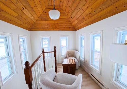 a living room with a wooden ceiling and windows at Saltwater Steeple in Port Saunders