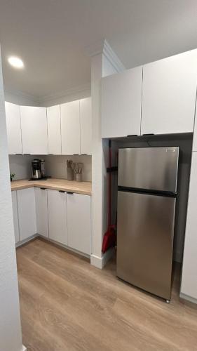 a kitchen with white cabinets and a stainless steel refrigerator at #4 Hygge Hus Hotel - Double Room Suite Connectable in Andrews