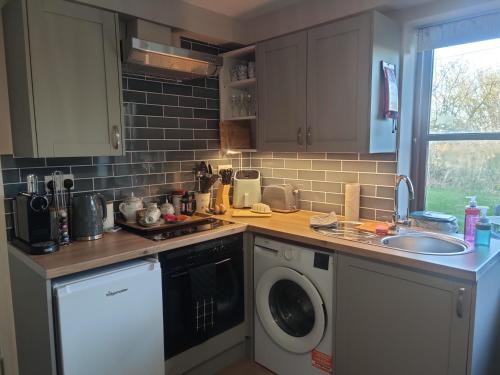 a kitchen with a sink and a washing machine at Tranquil Countryside Escape in Rural Kent- Pipistrelle View in Canterbury
