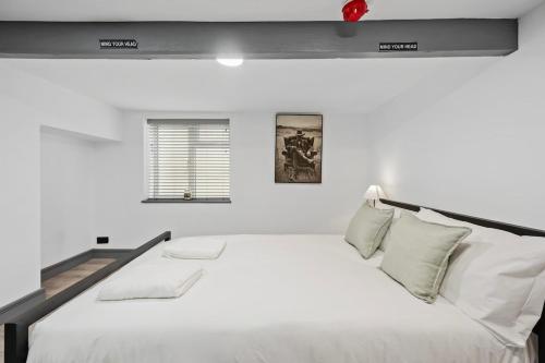 a white bedroom with a large white bed and a window at The Reading Hub in Reading