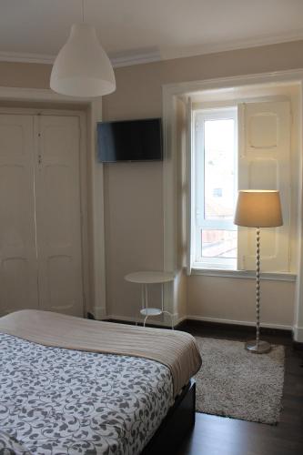 a bedroom with a bed and a lamp and a window at Suites & Apartments DP VFXira in Vila Franca de Xira