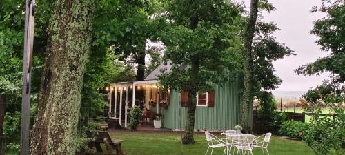 a green house with a table and chairs in the yard at Little Tin House in Van Reenen
