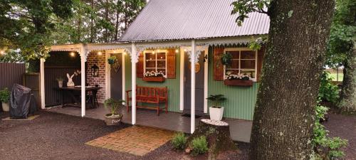 a green and white house with a table and a tree at Little Tin House in Van Reenen