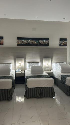 a bedroom with three beds and lights on the wall at فندق ثرا الرواد in Abu Arish