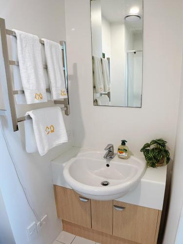 a bathroom with a sink and a mirror and towels at 2 FREE PARKING Penthouse with Harbour & Arena Views in Auckland