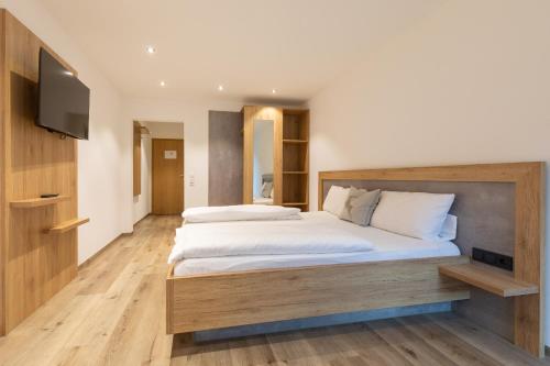 a bedroom with a large bed and a flat screen tv at Landgasthaus Grüner Baum in Simonswald