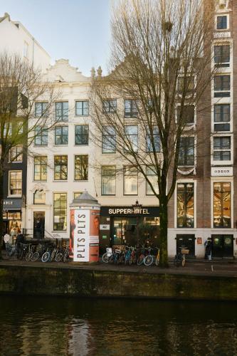 a building with bikes parked in front of a river at SUPPER Hotel in Amsterdam