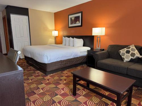 a hotel room with a bed and a couch at Baymont by Wyndham Plainfield/ Indianapolis Arpt Area in Plainfield