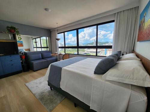 a bedroom with a large bed and a large window at Loft próximo à Oktoberfest Blumenau in Blumenau