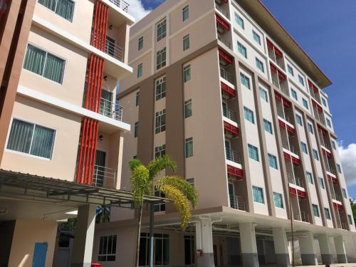 an apartment building with red and white windows and palm trees at TTT Hotel in Hat Yai