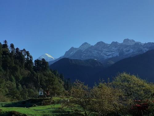 a house on a hill with mountains in the background at Kedar cloud camp in Kedārnāth