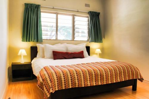 a bedroom with a large bed with a window at Victoria Apartments in Livingstone