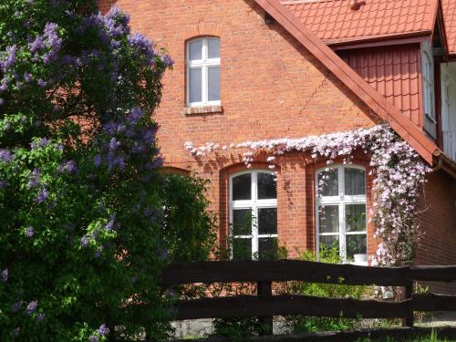 dom z czerwonej cegły z białymi oknami i ogrodzeniem w obiekcie Jeleńczówka Alte Dorfschule w mieście Parchowo