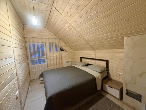 a small bedroom with a bed in a wooden room at Карпатська Тиша in Utoropy