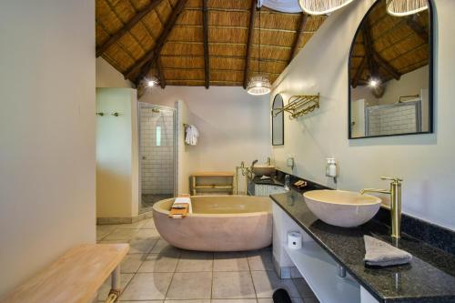 a bathroom with two sinks and a large tub at Mologa River Lodge in Rust de Winter