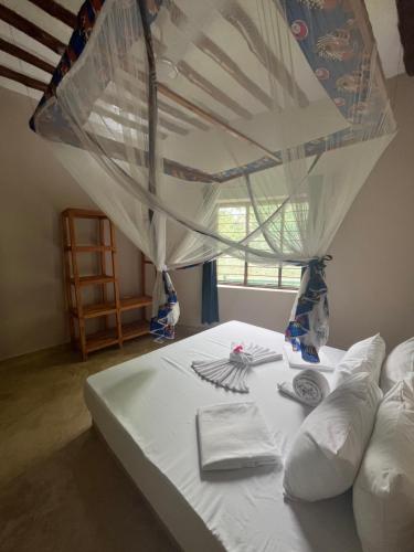 a white bed with a canopy in a room at Msafiri House in Kizimkazi