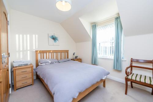 a bedroom with a bed and a chair and a window at Abbey View in Old Deer