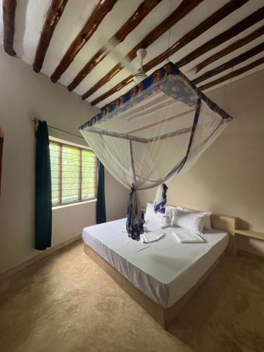 a bedroom with a bed with a mosquito net at Msafiri House in Kizimkazi