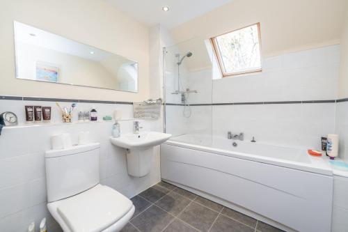 a white bathroom with a toilet and a tub and a sink at Abbey View in Old Deer
