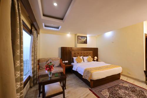 a bedroom with a bed and a chair and a table at The Summerlead, Shimla in Shimla