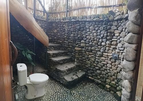 a stone bathroom with a toilet and a stone wall at SUMATRA ECORESORT in Bukittinggi