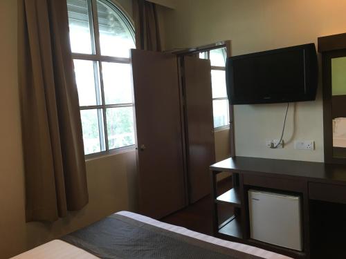 a bedroom with a bed and a television and a window at Lintas Plaza Hotel in Kota Kinabalu