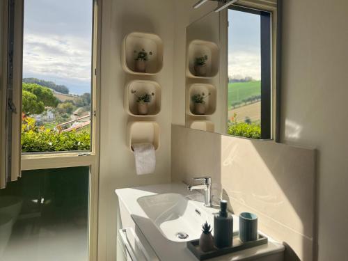 a bathroom with a sink and a mirror and a window at Respiro di Tramonto in Montegranaro