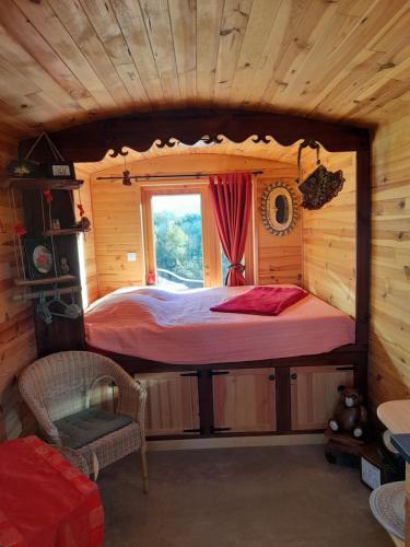 a bed in a log cabin with a window at Roulotte Manoé in Liéoux