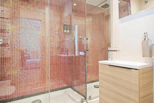 a bathroom with a glass shower and a sink at Beach Penthouse Sitges in Sitges