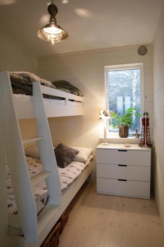 a bedroom with bunk beds with a desk and a window at Utsikten i Bua in Kungshamn