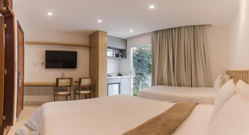 a hotel room with two beds and a television at Onda Lofts in Búzios
