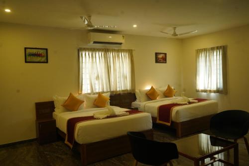 a hotel room with two beds and a table at Sesha Residency in Chennai