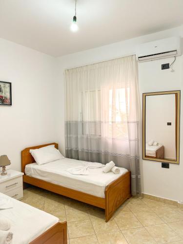 a bedroom with two beds and a mirror and a window at Xhoni's House in Sarandë