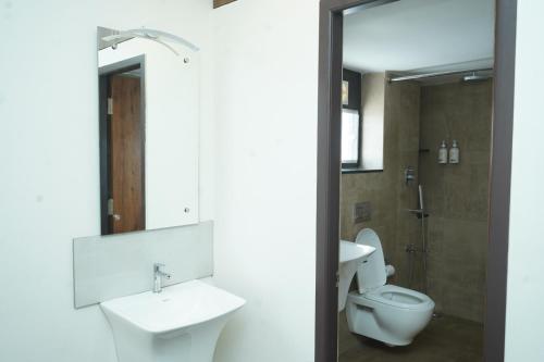 a bathroom with a toilet and a sink and a mirror at Sesha Residency in Chennai
