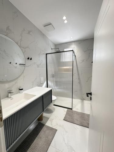 a white bathroom with a shower and a sink at Xhoni's House in Sarandë